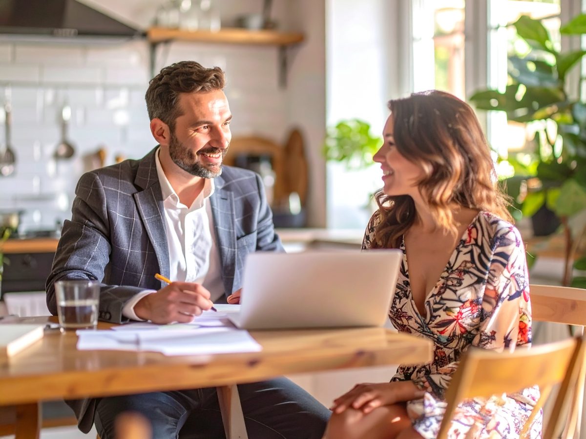 Two people talking through a home plan at a kitchen table.
